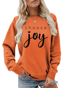 Detail of orange crewneck sweatshirt with choose joy text and ribbed cuffs