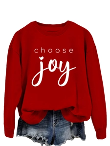 Detail of red crewneck sweatshirt featuring white choose joy text with a heart dot
