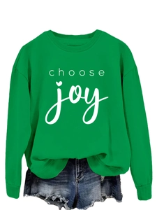 Detail of the white choose joy lettering and heart print on a green crewneck sweatshirt