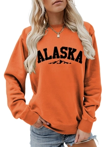 Detailed close-up of ribbed crew neck and Alaska mountain print on orange sweatshirt