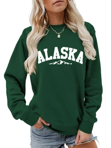 Close-up of deep green sweatshirt showing Alaska print and ribbed cuffs on a model