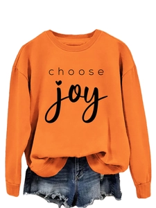 Close-up of vibrant orange sweatshirt with black 'choose joy' typography and round neck