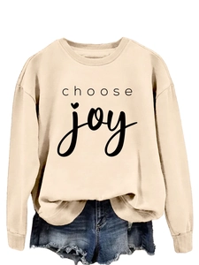 Close-up of Choose Joy letter print on apricot crewneck sweatshirt with heart detail