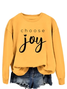 Detail of a bright yellow sweatshirt featuring Choose Joy text and frayed denim shorts