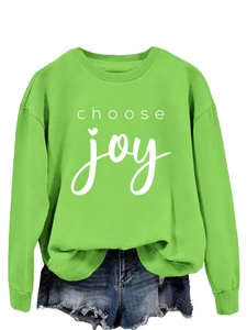 Detail of a bright green crewneck sweatshirt featuring white choose joy lettering