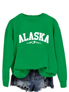 Detail of bright green crewneck ALASKA sweatshirt with mountain print and denim shorts