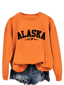 Detail of orange crewneck Alaska sweatshirt with mountain graphic and ribbed collar