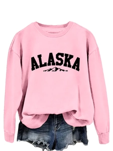 Close-up of Alaska mountain print and bold black lettering on pink crewneck sweatshirt