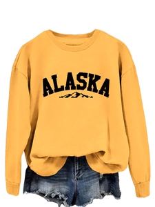 Detail view of yellow Alaska crewneck sweatshirt with mountain graphic and soft fabric texture