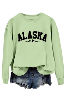 Close-up of mint green crewneck sweatshirt featuring Alaska mountain print and soft fabric