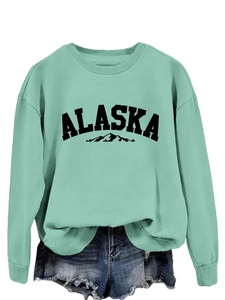Detail of mint green crew neck sweatshirt featuring ALASKA print and ribbed collar design