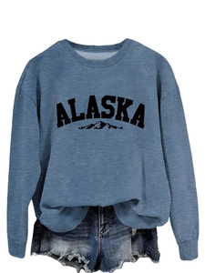 Close-up of blue crewneck sweatshirt featuring ALASKA mountain graphic and soft cotton texture