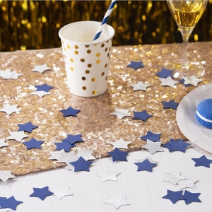 Primer plano de confeti de estrellas azules y plateadas brillantes en mesa de fiesta