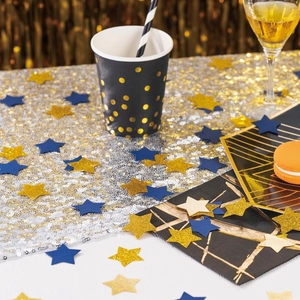 Primer plano de confeti de estrellas brillantes oro y azul sobre una mesa de fiesta formal