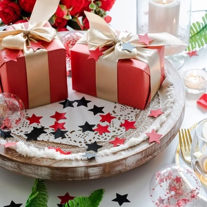 Primer plano de cajas de regalo rojas con lazos dorados y confeti de estrellas en bandeja