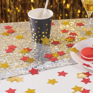 Primer plano de confeti de estrellas doradas brillantes y rojas en una mesa de fiesta