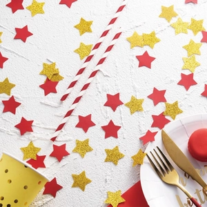 Primer plano de confeti de estrellas rojas y doradas brillantes en una mesa de fiesta