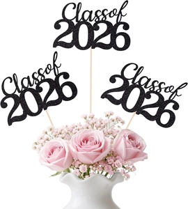Close-up of Class of 2026 black glitter cake toppers with floral arrangement background