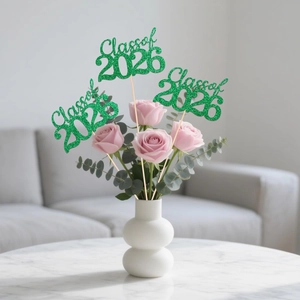 Close-up of Green glittery Class of 2026 cake toppers placed in a floral bouquet