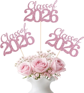 Pink glitter Class of 2026 cake toppers placed in a white flower vase with roses