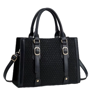 Retro black woven large tote bag with gold hardware and adjustable strap on white background