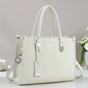 Detail view of cream leather tote bag with silver hardware and adjustable shoulder strap