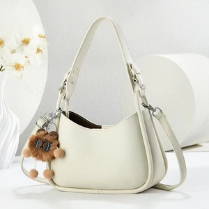 Dettaglio borsa in pelle crema a grana con tracolla larga e decorazione floreale