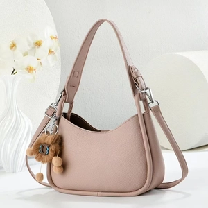 Dettaglio della borsa a mezzaluna in pelle rosa cipria con grana litchi e pendente