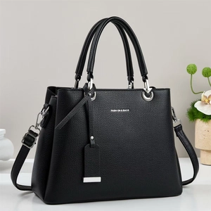 Detail of black lychee grain leather handbag with silver hardware and fashion text
