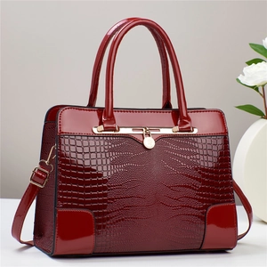 Detailed view of burgundy faux crocodile texture and glossy patent leather stitching