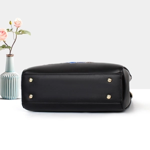 Detail view of the black embroidered bag bottom with golden metal feet for protection