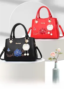 Detailed embroidery of peony flowers and butterfly on PU leather handbags with pompom