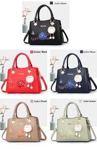 Close-up showing colorful floral embroidery and plush charms on PU leather handbags