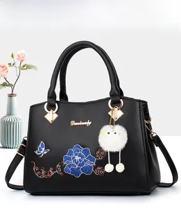 Detail of floral embroidery and gold hardware on black PU leather handbag for women