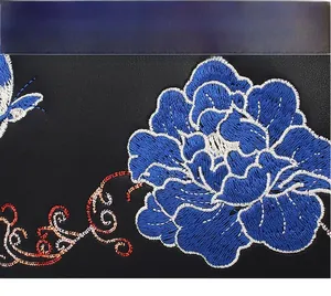 Detailed close-up of intricate blue floral and butterfly embroidery on black leather bag