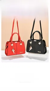 Detail view of red and black crocodile textured handbags with metallic hardware charms