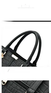 Detail of reinforced double handles on a black crocodile pattern faux leather handbag
