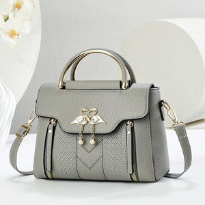 Macro detail of grey litchi leather bag with gold swan buckle and pearl charm