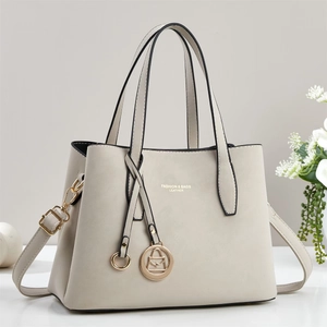 Détails d'un sac cabas pour femme avec pendentif doré rond et texte imprimé sur le cuir