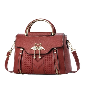 Red pebbled leather crossbody bag with swan heart clasp and golden metal top handle
