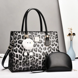 Detailed view of leopard print tote bag with small black pouch and plush charm