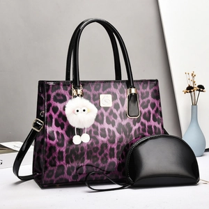 Detail of purple leopard print tote bag set with black patent leather trim and fur charm