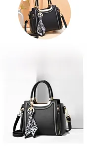 Detail of black leather handbag featuring white V-shaped stitching and leopard print scarf
