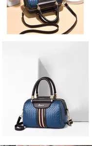 Macro view of navy woven texture pillow bag with leather handles and striped ribbon