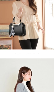 Detail of a black leather handbag with a leopard print scarf and silver zipper details