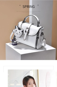 Close-up of white crossbody bag with cute cat coin purse charm and metal hardware detail