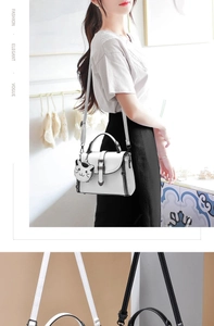 Detail of white mini crossbody bag with metal twist lock and cute black cat charm