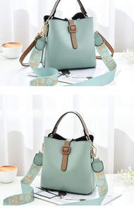 Detail of mint green bucket bag with brown contrast strap and wide floral textile strap