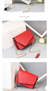Detail of red crossbody bag with V-shaped flap, brand logo and golden chain strap