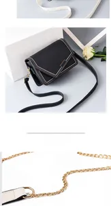 Detail of black leather crossbody bag with contrast stitching and golden chain strap